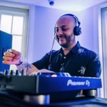 A man with a beard and tattoos wearing headphones and a patterned shirt